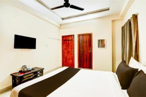 a bedroom with a bed and a flat screen tv at Hotel O Vyb Hotels in Hyderabad +24 photos