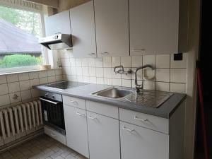a kitchen with white cabinets and a sink and a window at Villa Duinpieper in De Panne