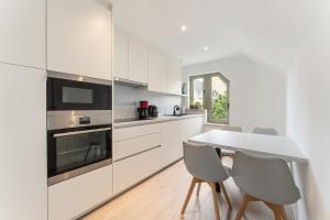 une cuisine avec des armoires blanches et une table et des chaises dans l'établissement Marlie s Home - comfort stadsapp met zonnig terras, à Nieuport