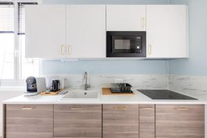 a white kitchen with a sink and a microwave at Le Petit Monet - City center near train station in Vernon +6 photos