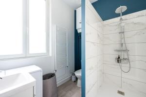 a white bathroom with a shower and a sink at Le Petit Monet - City center near train station in Vernon