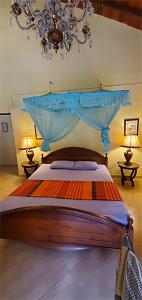 a bedroom with a bed with a blue canopy and two lamps at Hantana Forest Reserve Inn in Kandy