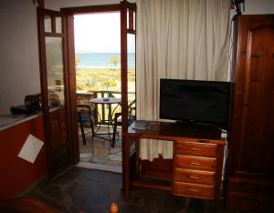 a living room with a television on a desk with a view of the ocean at Drapanias BeachFront Apartments - Marinakis in Kissamos