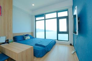 a bedroom with a bed and a desk and a large window at Sunrise from bed Apartment - NhaTrang Beach in Nha Trang
