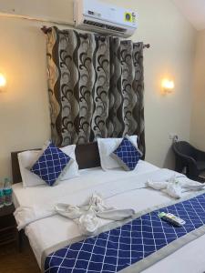 a bed in a room with blue and white pillows at Baga Beach Palms in Baga