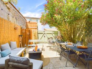 a patio with a couch and a table and chairs at À 750m des plages, jolie maison pour 4 in Saint-Clément-des-Baleines
