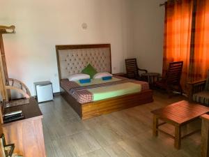 a bedroom with a bed with chairs and a table at Hotel Vish Ceylon in Talawatugoda