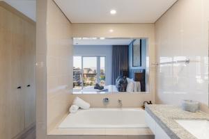 ケープタウンにあるHarbour's Edge Walk to V & A Waterfront and CTICCの浴槽、洗面台、鏡のあるバスルーム +26枚の写真