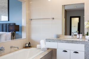 ケープタウンにあるHarbour's Edge Walk to V & A Waterfront and CTICCの白い浴槽と洗面台のあるバスルーム