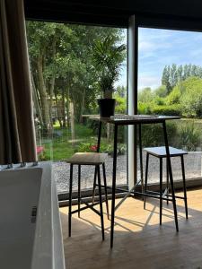 a table and two stools in front of a window at L'Escapade du marais in Guînes +10 photos
