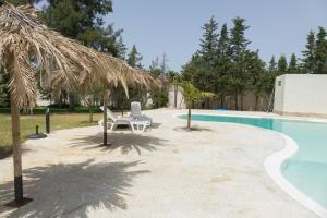 a swimming pool with two chairs and a umbrella at Chalet El Molino in Chiclana de la Frontera