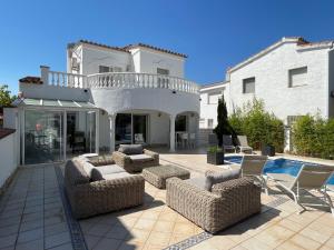 a house with a patio with chairs and a pool at Cap Ras in Empuriabrava