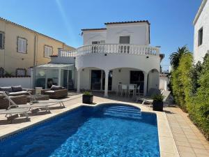 a villa with a swimming pool in front of a house at Cap Ras in Empuriabrava