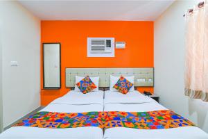 a bedroom with a bed with an orange wall at FabHotel VRJ Residency - 500M from Chennai Trade Center in Chennai