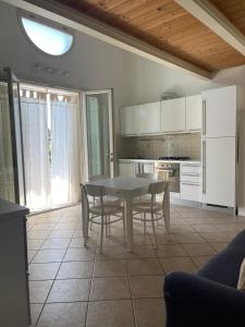 una cucina con un tavolo e sedie in una stanza di Appartamento IL GLICINE a piano terra zona tranquilla a due passi dal mare a Lido di Savio