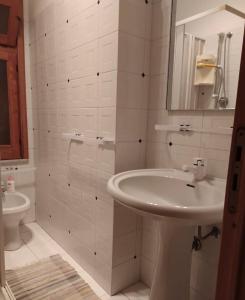 un bagno bianco con lavandino e specchio di Savoca Apartment a Giardini Naxos