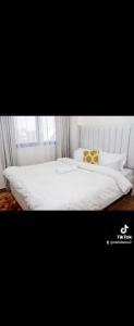 a white bed with white sheets and pillows on it at Luxore appartments in Nairobi