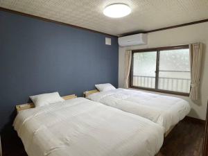 旭川市にあるHarry's Ski House ASAHIKAWAの青い壁のベッドルーム1室(ベッド2台付)