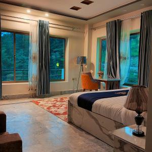 a bedroom with a bed and a desk and windows at Hilton Resort Malamjabba by Khan Familia Travels in Malam Jabba