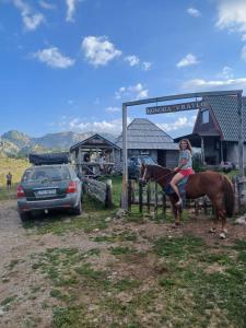 a woman riding a horse next to a car at Konoba Vratlo Sinjajevina Ječmen Do in Kolašin