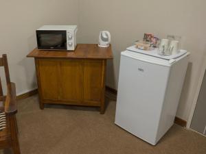 a microwave sitting on top of a table with a refrigerator at In die Veld Guest Rooms in Bloemfontein