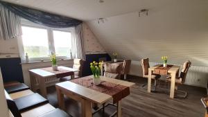 a dining room with tables and chairs and a window at Pension Sandra in Neuharlingersiel