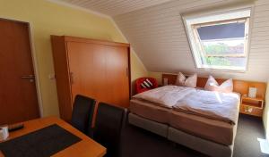 a bedroom with a bed and a table and a window at Pension Sandra in Neuharlingersiel +12 photos