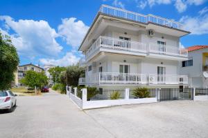 a white apartment building with white balconies and a car at Mythodea Home Apartments in Limenas