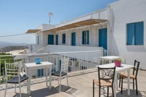 a balcony with tables and chairs and a building at Politimi Studio N8 in Amorgos