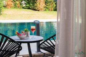 a table with a glass of wine and two chairs at Alkyon Hotel in Limenas