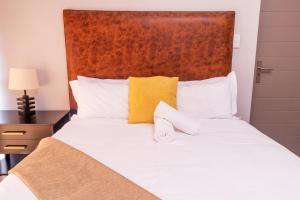 una camera da letto con un letto con lenzuola bianche e cuscini gialli di 8 Elizabeth place - Beautiful self catering 1 Bedroom Apartment next to Kyalami Racetrack in Midrand with Free Wifi Local swimming pool Gym and Restaurant - perfect for a couple a Midrand Altre 35 foto