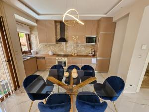 une salle à manger avec une table en verre et des chaises bleues dans l'établissement Agora Luxury Villa II, à Loutraki