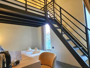 a loft bedroom with a staircase and a chair at Georgetown AY Hotel in George Town