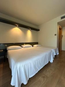 a large white bed with white sheets and pillows at Hotel Parigi 2 & Spa in Dalmine