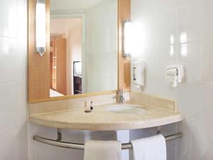 un baño con lavabo y espejo en Ibis Merida, en Mérida