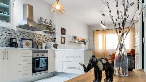 eine Küche mit weißen Schränken und einer Vase in der Unterkunft Beachhouse Gran Tarajal 3BR in Gran Tarajal