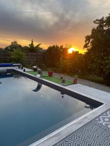 a swimming pool with the sunset in the background at Au calme dans le marais avec piscine in Yves