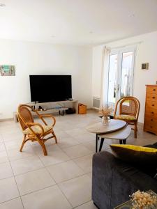a living room with a couch and chairs and a tv at Le P tit Jard proche de la plage in Jard-sur-Mer