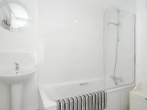 une salle de bain blanche avec une douche et un lavabo dans l'établissement Stone's Throw Cottage, à Launceston 21 autres photos