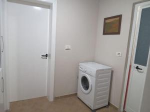een wasmachine in een witte kamer met een deur bij The Little Oasis Villa in Shkodër