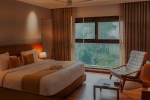 a bedroom with a bed and a chair and a window at The Valle by Kondody Hotels in Munnar +98 photos
