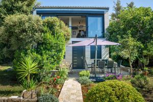 a house with an umbrella and a table and chairs at Apartman Fjaka in Petrcane