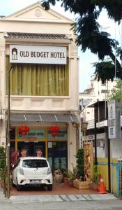 um carro branco estacionado em frente a um antigo hotel económico em Old Budget Hotel em George Town