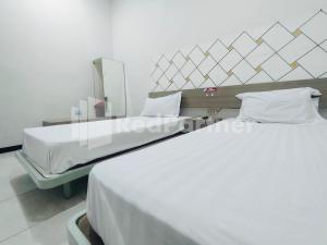 une chambre d'hôpital avec deux lits et un miroir dans l'établissement Almeira Homestay Syariah Near RS Islam Al-Irsyad Mitra Reddoorz, à Surabaya