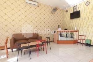 un salon avec un canapé, des tables et des chaises dans l'établissement Almeira Homestay Syariah Near RS Islam Al-Irsyad Mitra Reddoorz, à Surabaya