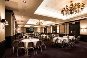 雷丁pentahotel Reading的宴会厅配有桌椅和吊灯。