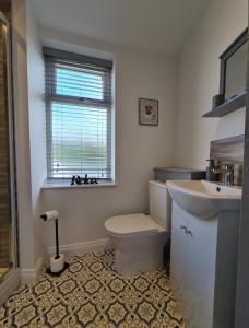 a bathroom with a toilet and a sink and a window at Cosy Mytholmroyd Getaway in Mytholmroyd