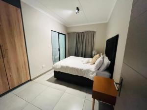 ein Schlafzimmer mit einem Bett und einem Stuhl darin in der Unterkunft 13 Elizabeth Place - Beautiful 2 bedroom unit next to Kyalami Racetrack with free WiFi - swimming pool gym and restaurant - Perfect for a small family in Midrand Waterfall in Midrand + 34 Fotos