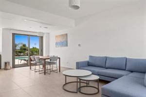 Una sala de estar con un sofá, una mesa y sillas. en Serenity Waves Villa 16, en Lárnaca
