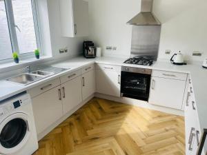 a kitchen with white cabinets and a wooden floor at Marine Cottage 2 - With Private Hot Tub in Newbiggin-by-the-Sea +7 photos
